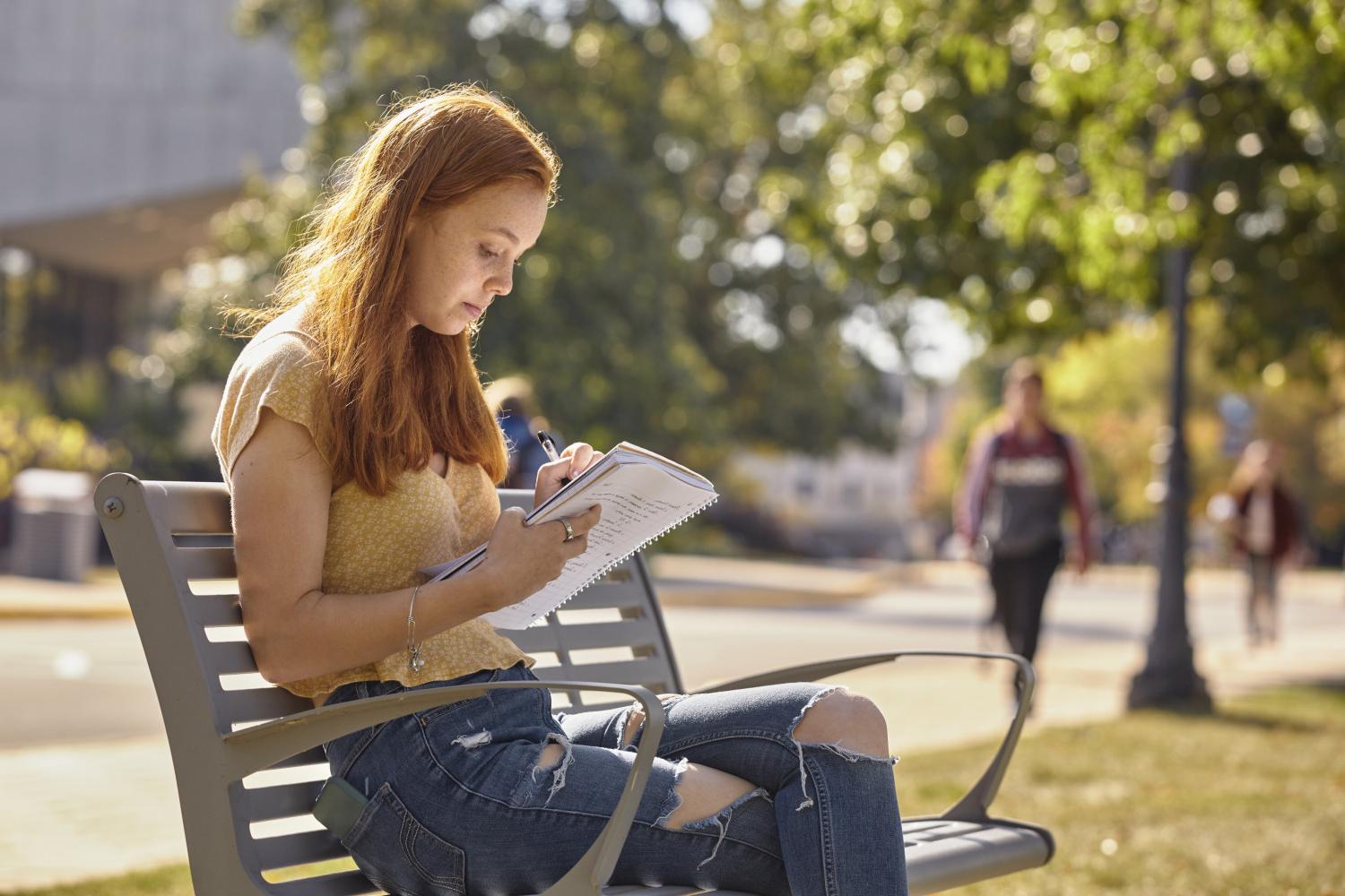 一位<a href='http://h6i.goudounet.com'>全球十大赌钱排行app</a>学院的学生在校园里的长椅上读书.